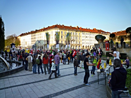 La-Spezia-Platz mit Kundgebungsteilnehmern, Kindern, die Atommülldosen umwerfen und einem AKW aus Pappe